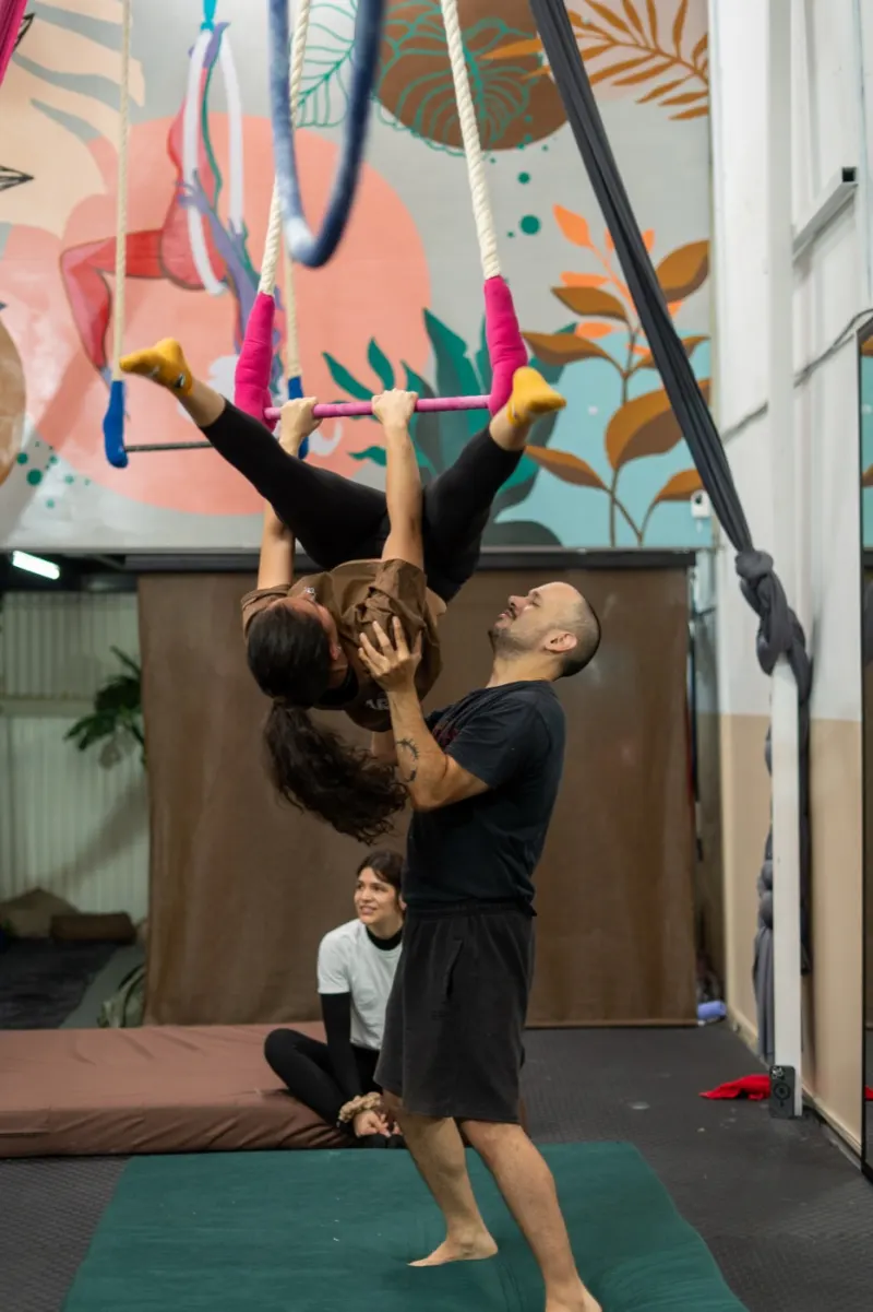 Profe de Volaria acompañando a una alumna en el trapecio